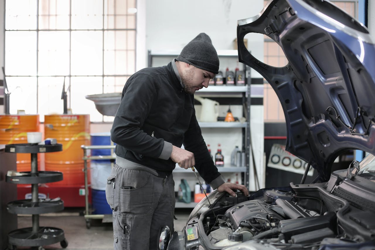 who-we-are Mechanic checking a car engine in a garage, ensuring quality maintenance and repair.