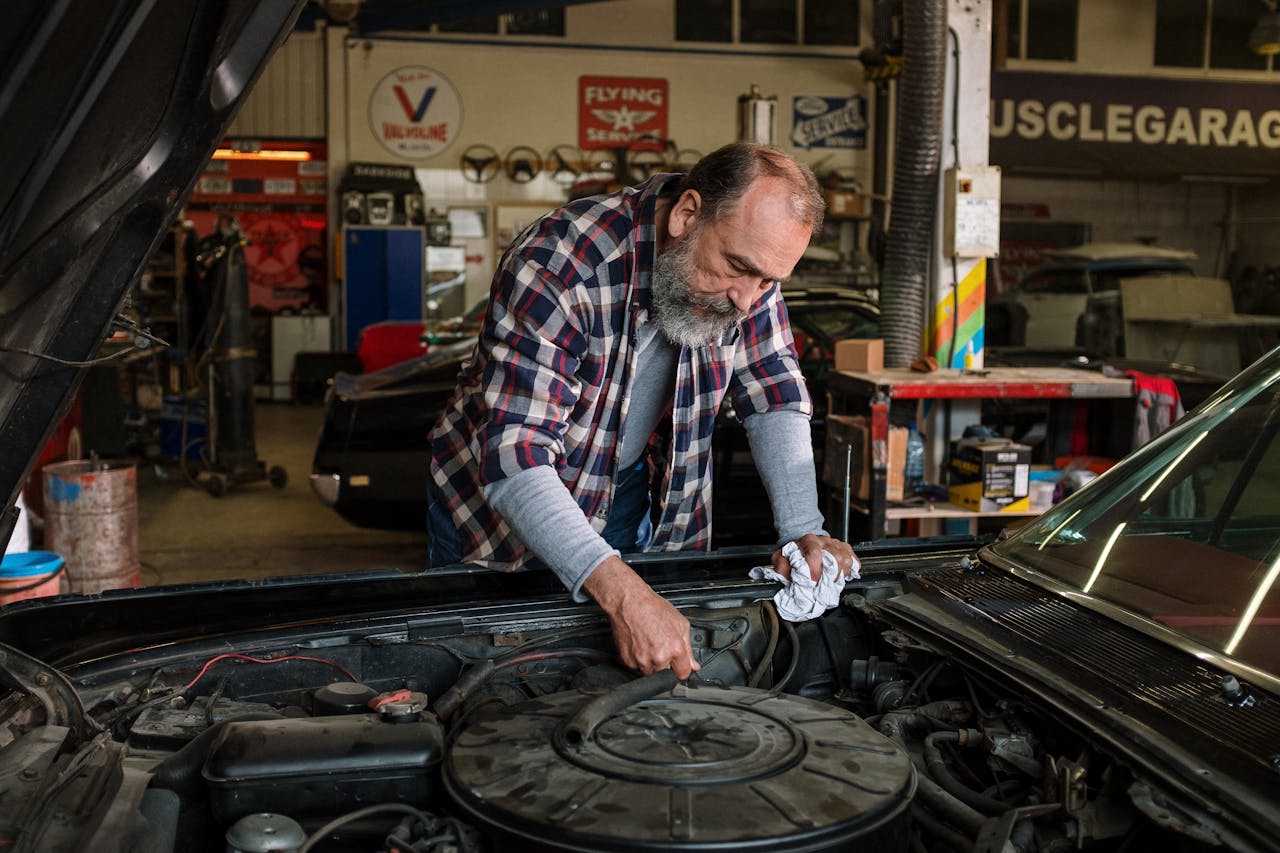 about-us Bearded mechanic working on engine repair in an auto repair shop garage with a focus on hands-on car service.