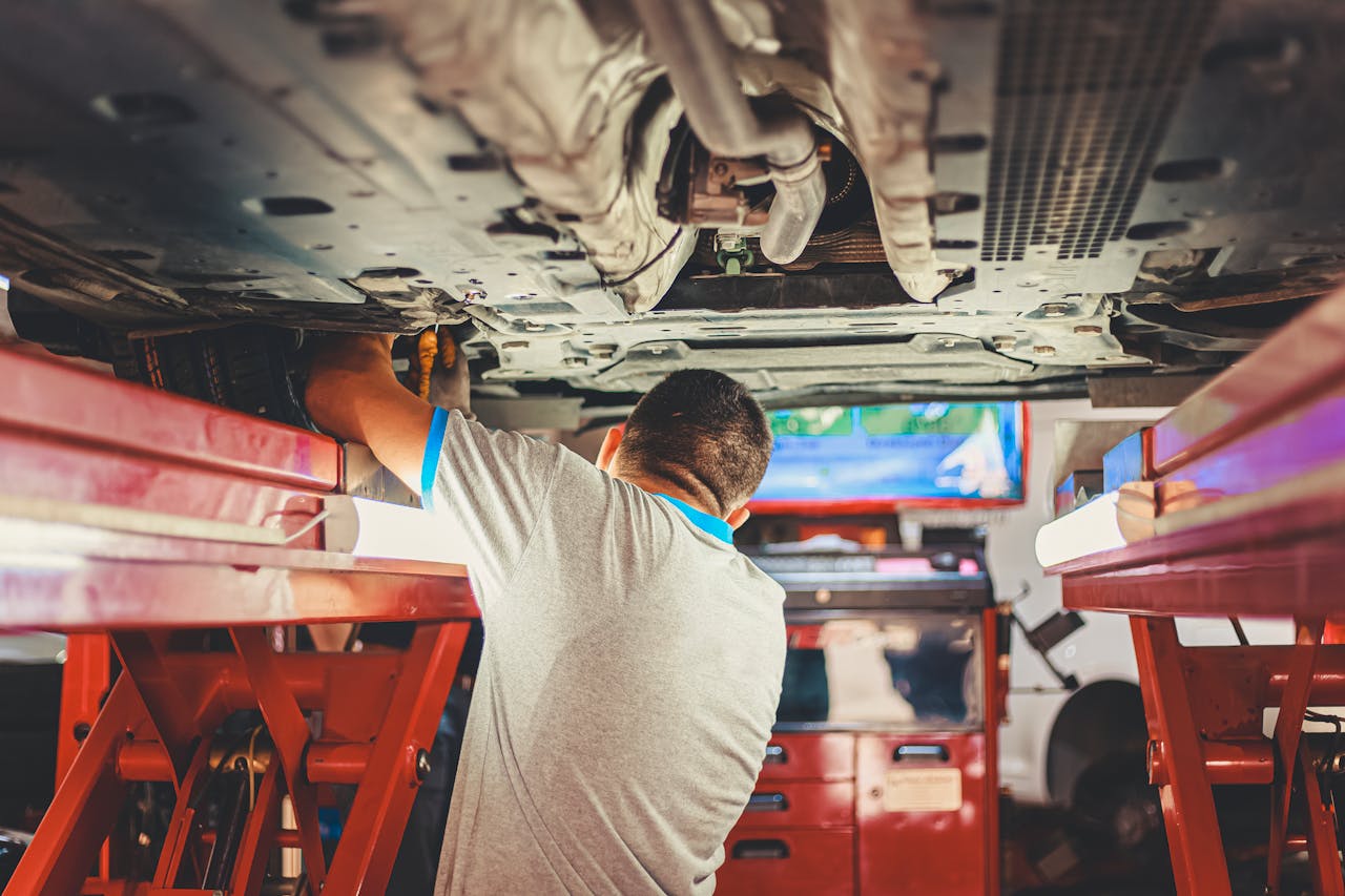 home-hero A mechanic works under a lifted car in an auto repair shop, adjusting parts.