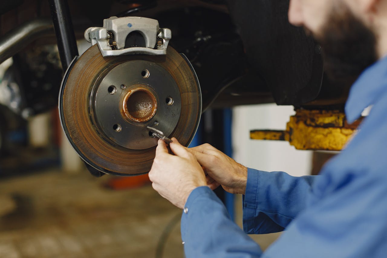 get-in-touch Mechanic working on brake disc in an auto repair workshop, close-up, focus on hands.