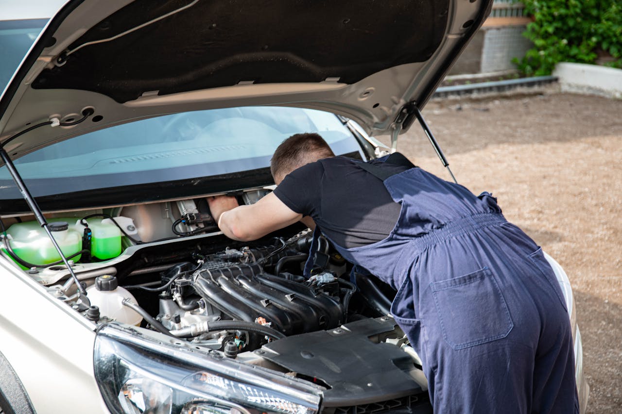 about-bg Mechanic repairing car engine in daylight, showcasing technical skills.